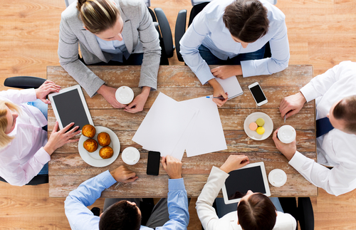 business, people, break and team work concept - close up of creative team meeting and drinking coffee with muffins during lunch in office